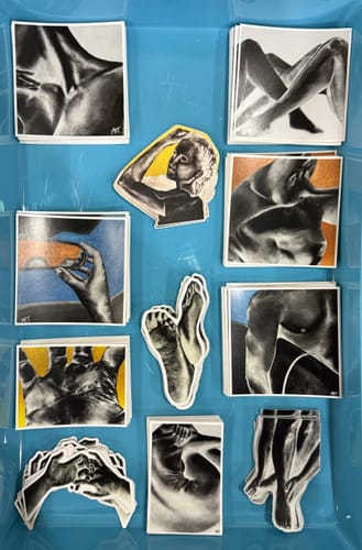 Customer's custom Square Stickers featuring various black and white art prints, spread out in a blue tray.