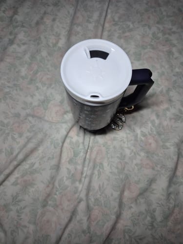 Customer's ONE Lid installed on a dark insulated tumbler resting on a floral patterned surface.