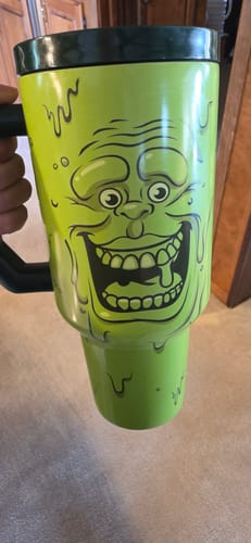 Customer's neon green Thicc Buddy 50oz Slimer mug with a dark lid, held by a hand.