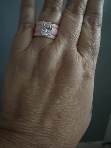 Customer's hand wearing two light pink silicone rings with a large emerald-cut cubic zirconia stone.