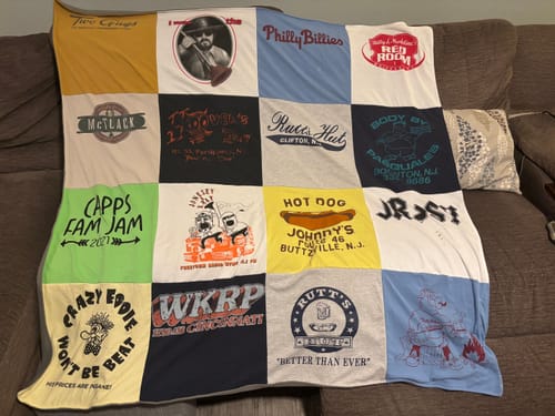 Customer's Project Repat T-Shirt Quilt featuring a patchwork of colorful vintage graphic t-shirts spread on a couch.