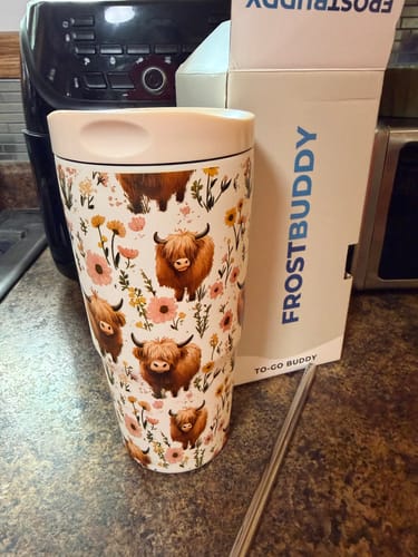Customer's Highland Cow To-Go Buddy tumbler sitting next to its product box on a kitchen counter.
