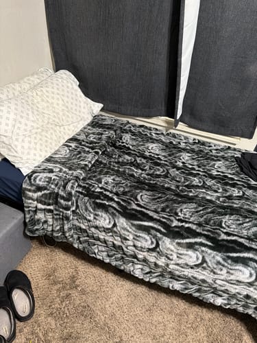 Customer's Hugs Marble Onyx Blanket spread neatly across a bed, showing a dark, swirling marble pattern.