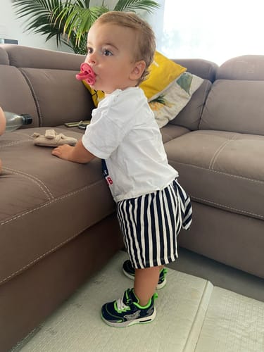 Customer's child wearing a pink Chupete DIAMOND FS while standing in a living room.