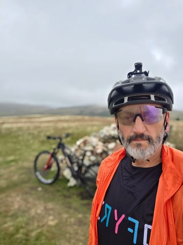 Customer's Deathray cycling glasses with purple photochromic lens worn by person outdoors with a mountain bike.