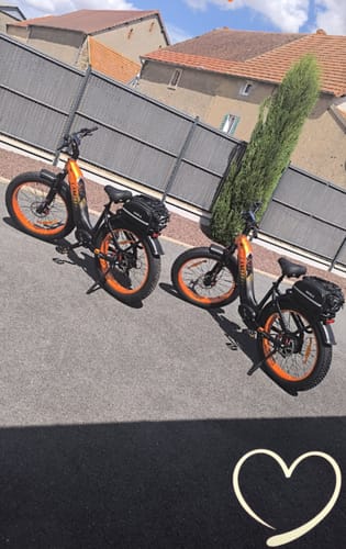 Customer's two orange and black Lankeleisi MG600 Plus E-Bikes parked outdoors on a paved area.