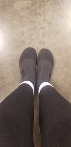 Customer's feet wearing the black Otishi 2.0 shoes with dark leggings and white socks.