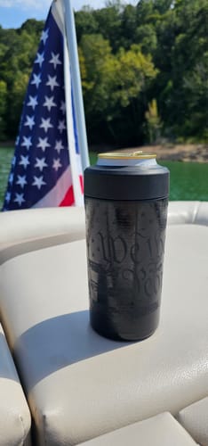 Customer's Universal Buddy 1776 Edition black metal can cooler holding a beverage on a boat with an American flag nearby.