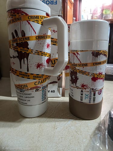 Customer's two Thicc Buddy 40oz mugs featuring crime scene tape and bloody handprint designs on a counter.