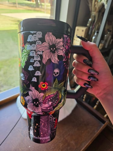 Customer's Thicc Buddy mug in Toxic Bloom print, held by a hand with dark decorative nail art.