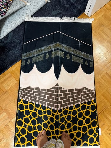 Customer's Kaaba Corner Padded Prayer Mat with black, gold, and cream geometric print on a wood floor.
