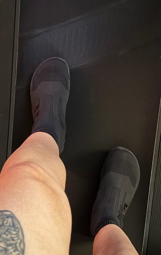 Customer's black Otishi 2.0 shoes worn on a treadmill while training.