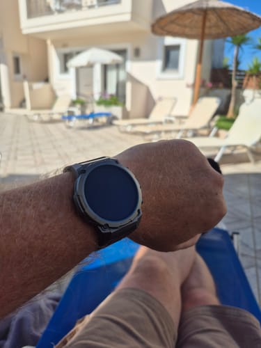 Customer's Gard Pro Ultra 3 watch with black screen, worn on wrist while sitting on a pool lounge chair.