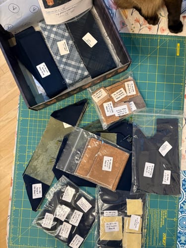 Customer's Midnight Pines quilt kit with pre-cut fabric pieces, labeled bags, and pattern inside a box.