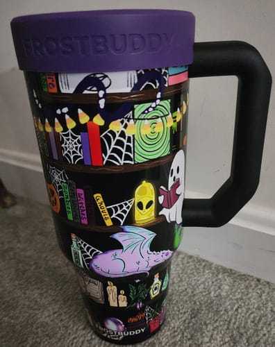 Customer's Thicc Buddy mug with spooky shelf print and a purple rim against a white wall.