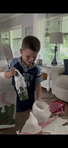 Customer's child holding a baseball-themed Bottle Buddy 16oz in a living room.