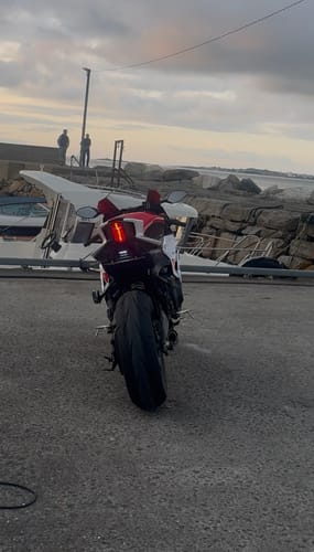 Customer's motorcycle with a installed Locking Shim visible on the rear plate bracket, parked outdoors by a harbor.