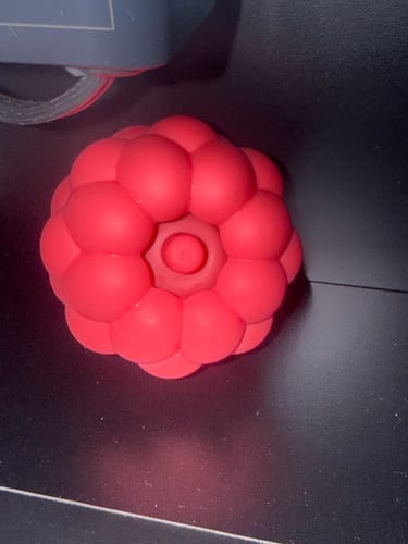 Customer's bright red Berri clitoral massager, showing the spherical textured surface and center point.