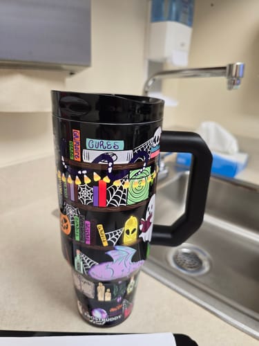 Customer's black Thicc Buddy mug with a Halloween-themed bookshelf print, resting near a kitchen sink.