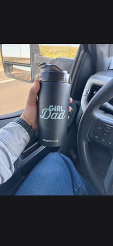 Customer's hand holding a black Girl Dad Universal XL stainless steel cup inside a vehicle.