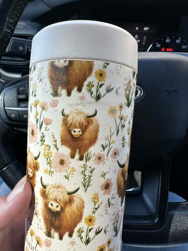 Customer's Highland Cow Universal Buddy can cooler held in a hand inside a vehicle.