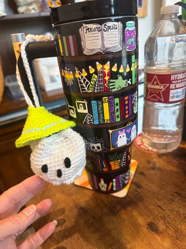Reviewer's Thicc Buddy mug featuring a bookshelf pattern, with a small crocheted ghost pouch hanging from the handle.