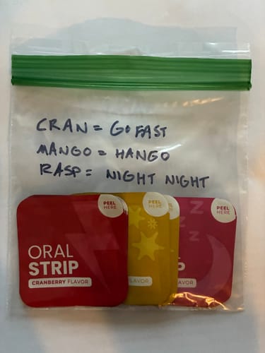 Customer's Bail Out oral strips in a plastic bag with handwritten notes labeling cranberry, mango, and raspberry flavors.