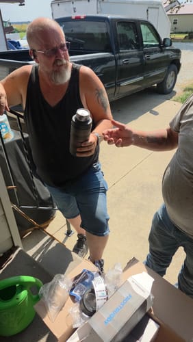 Customer's Universal XL Bourbon Barrel cup held by a person in a driveway with a truck in the background.