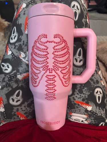 Customer's pink Thicc Buddy 40oz mug featuring a rhinestone rib cage design against a patterned spooky background.