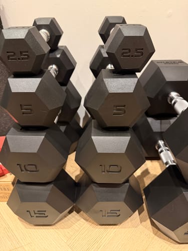 Customer's ATLETICA Hexagon Hanteln PRO in a stack of various weight sizes on a wooden floor.