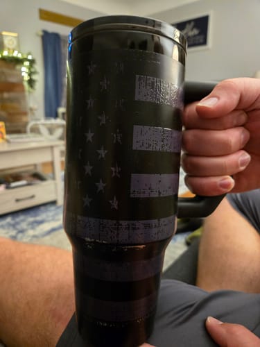 Customer's Thicc Buddy 40oz tumbler in gunmetal, held in hand, featuring a distressed American flag design.