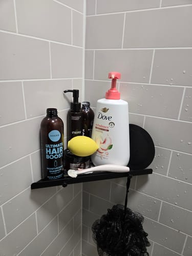 Customer's yellow Lem clitoral massager sitting on a bathroom shower shelf among various toiletry bottles.