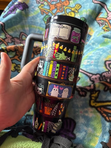 Customer's Thicc Buddy mug held in hand, featuring a dark bookshelf pattern with ghosts, potions, and spell books.