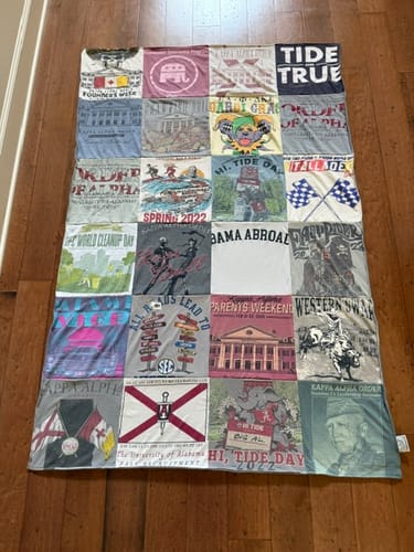 Customer's Project Repat T-Shirt Quilt featuring various college fraternity shirts, laid flat on a wooden floor.