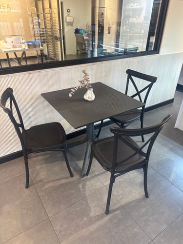 Customer's black Crossback Danubio chairs arranged around a square table in a restaurant setting.