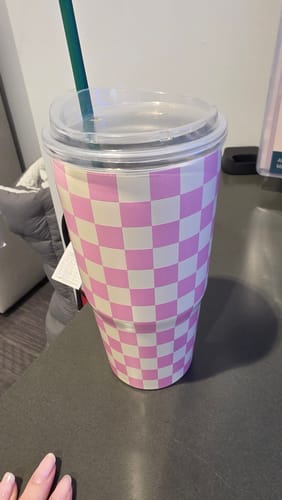 Customer's To-Go Buddy pink checkered cup on a surface with a green straw and clear lid.