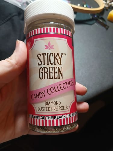 Customer's hand holding the Sticky Green Candy Collection Diamond Dusted Pre Rolls jar.