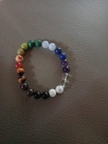 Customer's Bracelet chakras made of multi-colored natural stone beads arranged in a circle on a flat surface.