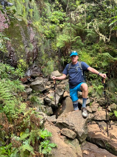 Customer's Rugova Pro 3 Wanderstöcke in use by a hiker on a rocky, forested path near a waterfall.