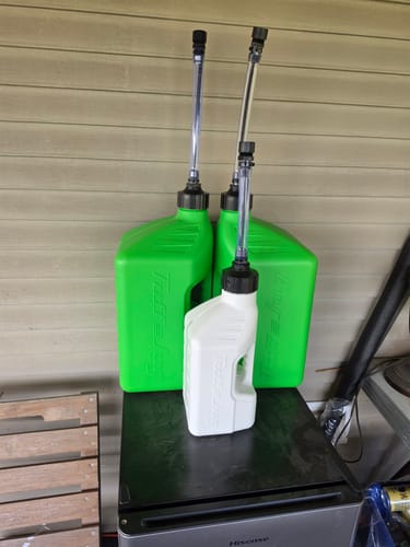Reviewer's two green and one white plastic fuel jugs with tall spouts sitting on a counter.