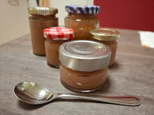 Reviewer's Mangostan Frucht-Marmelade in verschiedenen kleinen Gläsern mit einem Löffel auf einem Holztisch.