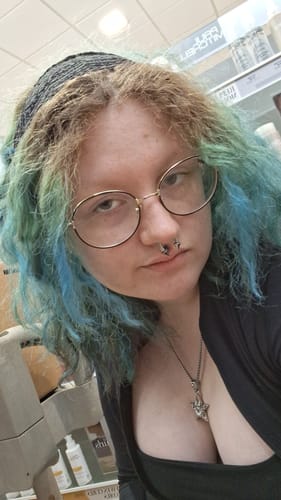Customer's SKAR pendant worn as a silver star necklace by a person with blue and brown hair.