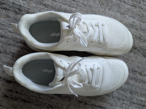 Customer's pair of white CUURT Muuv court shoes viewed from above, sitting on a carpeted surface.