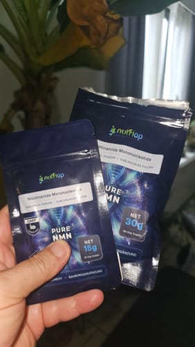 Customer's hand holding a 15g and a 30g pouch of Nutriop Pure NMN Sublingual Powder.