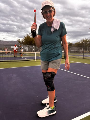 Reviewer standing on a pickleball court wearing white CUURT Muuv wide toe box court shoes.