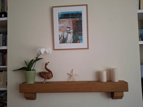 Customer's Rustic Oak Beam Shelf with Corbels mounted on a light wall, styled with a plant, ornaments, and candles.