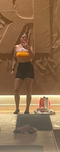 Reviewer in athletic wear standing in a gym, showing physical results after using Melt.