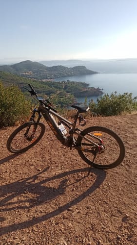 Customer's Lankeleisi MG600 Pro e-mountain bike parked on a dirt trail overlooking a scenic bay.