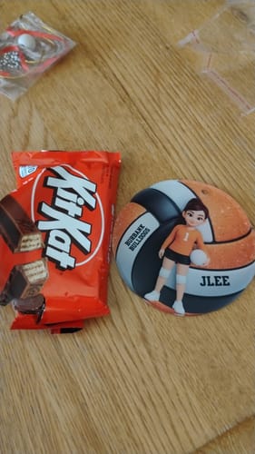 Customer's personalized volleyball acrylic ornament with a cartoon player, placed next to a candy bar on a wood table.