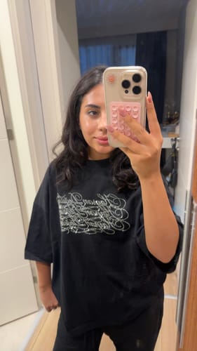 Customer's Radikal Merch Hayran Değilim siyah boxy tişörtü giymiş, aynada kendine bakıyor.